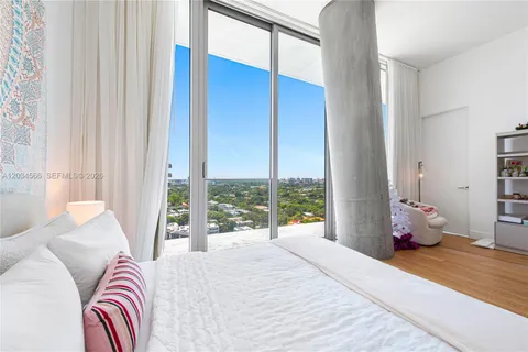 a bedroom with a bed and large windows
