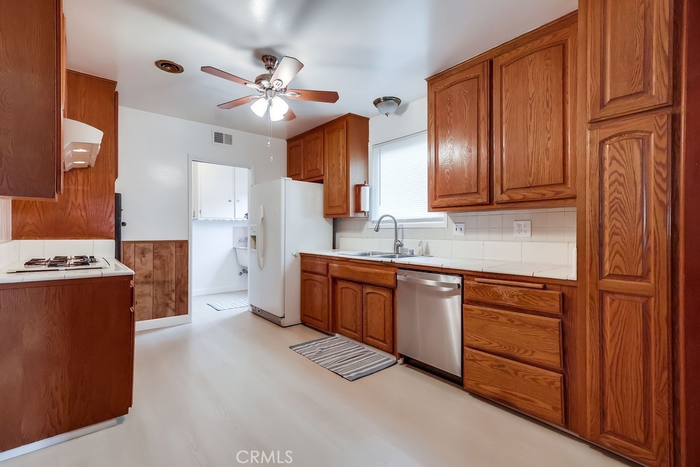 11639 Harvard Drive Norwalk, CA 90650 - Photo 13 of 33 a kitchen with stainless steel appliances granite countertop a refrigerator a stove and a sink with wooden cabinets