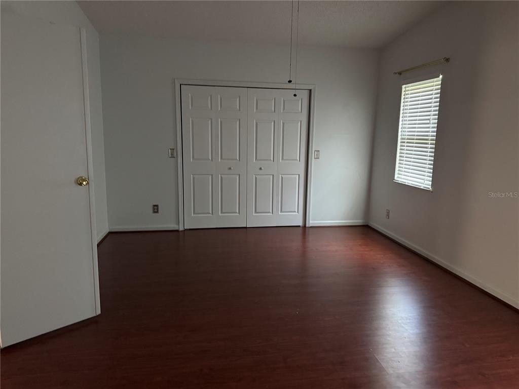 1605 Cherry Hill Road Lady Lake, FL 32159 - Photo 11 of 14 an empty room with wooden floor and windows with curtains