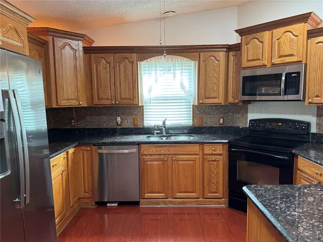 a kitchen with stainless steel appliances granite countertop a stove a sink and a refrigerator