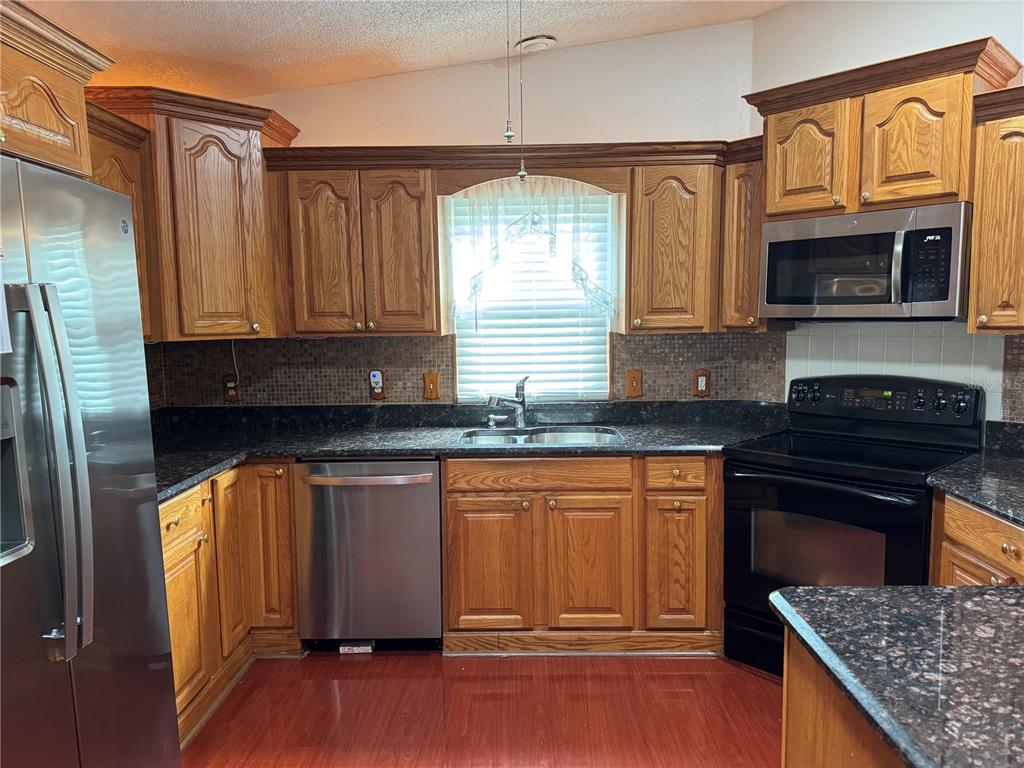 1605 Cherry Hill Road Lady Lake, FL 32159 - Photo 3 of 14 a kitchen with stainless steel appliances granite countertop a stove a sink and a refrigerator