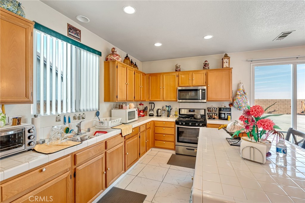 11036 Windcrest Court Adelanto, CA 92301 - Photo 11 of 45 a kitchen with a sink stove and cabinets