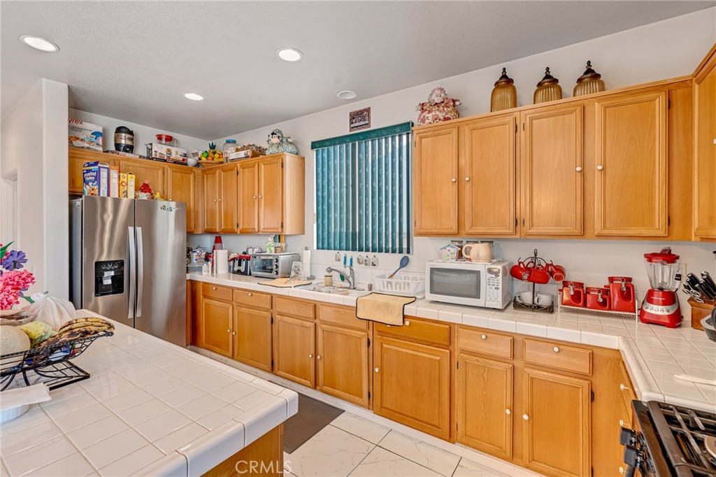 11036 Windcrest Court Adelanto, CA 92301 - Photo 12 of 45 a kitchen with stainless steel appliances sink refrigerator and window