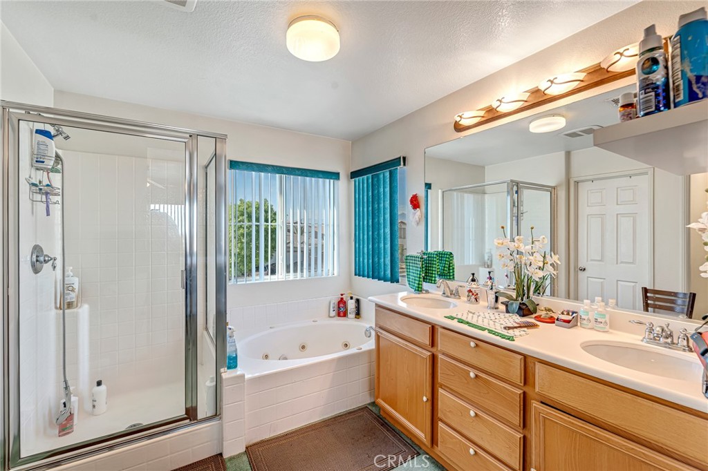 11036 Windcrest Court Adelanto, CA 92301 - Photo 21 of 45 a bathroom with a tub a double vanity sink a mirror a shower and vanity