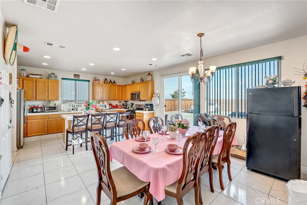11036 Windcrest Court Adelanto, CA 92301 - Photo 30 of 45 a dining room with stainless steel appliances kitchen island granite countertop a dining table and chairs