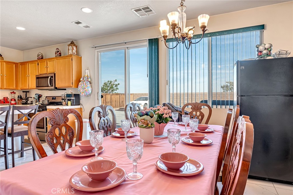 11036 Windcrest Court Adelanto, CA 92301 - Photo 31 of 45 a view of a dining room with furniture a chandelier and wooden floor