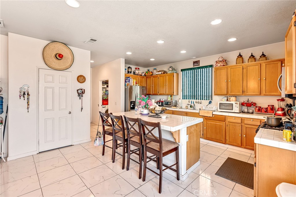 11036 Windcrest Court Adelanto, CA 92301 - Photo 8 of 45 a kitchen with stainless steel appliances kitchen island granite countertop a table and chairs in it