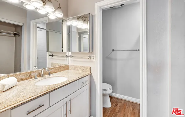 a bathroom with a granite countertop sink a toilet and a mirror