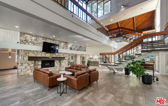 a living room with furniture a fireplace kitchen view and a flat screen tv