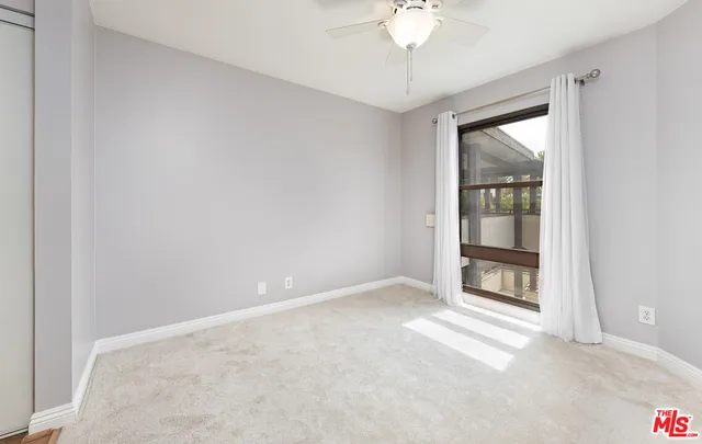an empty room with a chandelier fan and windows