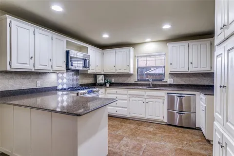 a kitchen with granite countertop white cabinets and stainless steel appliances