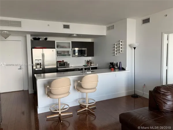 a kitchen with stainless steel appliances kitchen island granite countertop a refrigerator a stove a sink and chairs