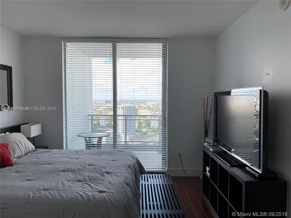 a bedroom with a bed flat screen tv and a window