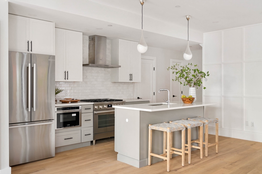 a kitchen with stainless steel appliances a stove a sink a refrigerator and a wooden floor