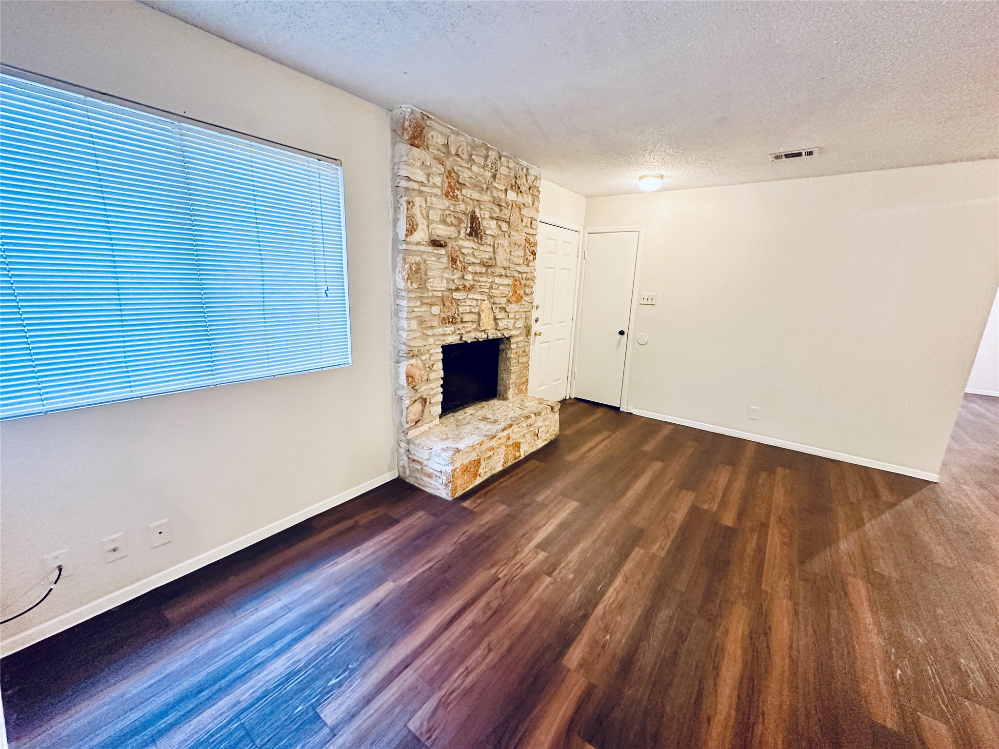 12505 Turtle Rock Road, Unit A Austin, TX 78729 - Photo 19 of 38 A spacious living area featuring rich hardwood-style flooring and a prominent stone fireplace hearth.