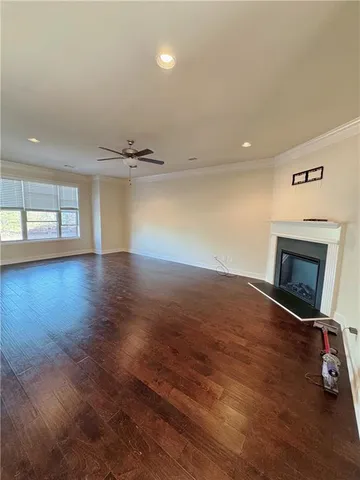 an empty room with wooden floor fireplace and windows
