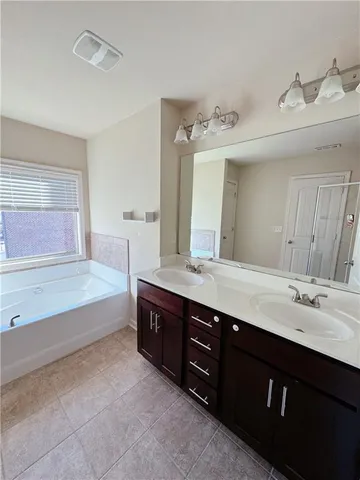 a spacious bathroom with a granite countertop double vanity sink a mirror and a bathtub