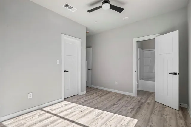 an empty room with a hardwood and ceiling fan