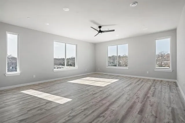 a view of empty room with wooden floor and fan