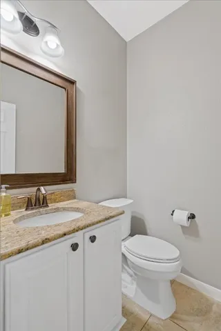 a bathroom with a granite countertop toilet sink and mirror