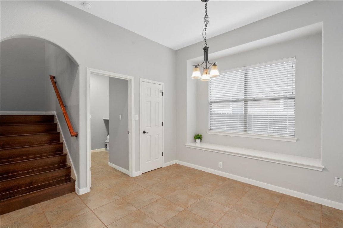 1813 Tall Chief Leander, TX 78641 - Photo 14 of 26 Unfurnished dining area with baseboards, stairs, light tile patterned flooring, and a chandelier