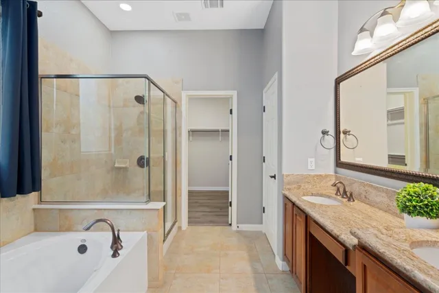 a bathroom with a granite countertop tub sink a mirror and shower