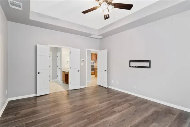 an empty room with wooden floor and ceiling fan