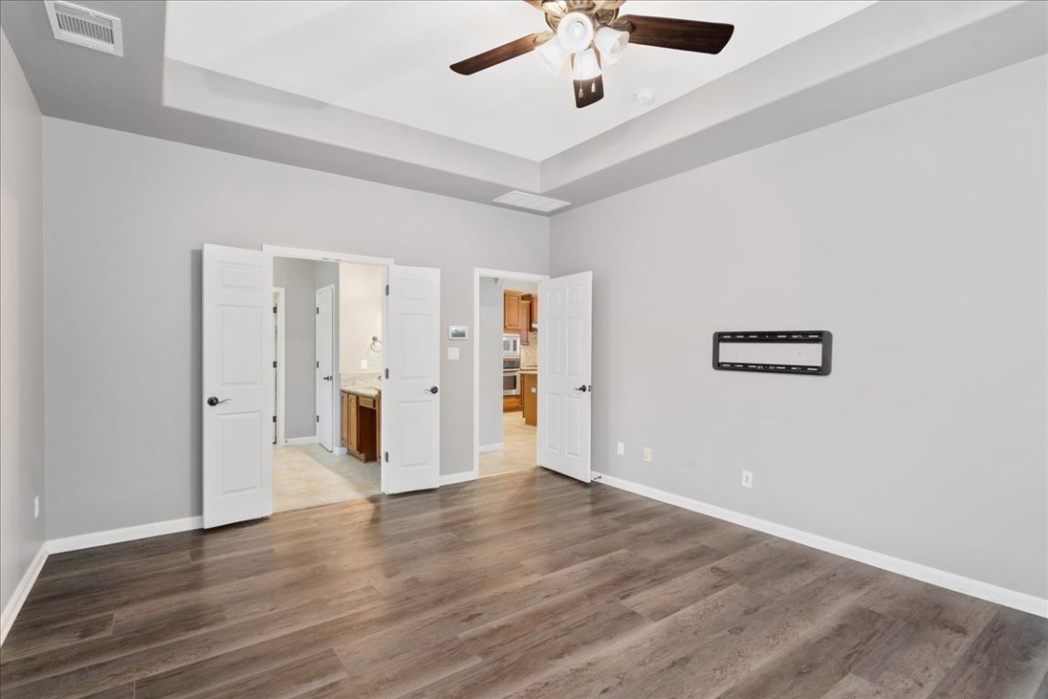 1813 Tall Chief Leander, TX 78641 - Photo 17 of 26 Unfurnished bedroom featuring baseboards, a tray ceiling, visible vents, and wood finished floors