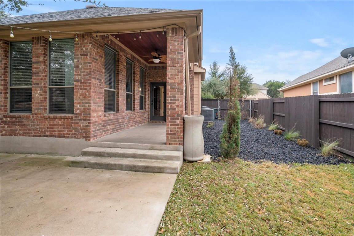 1813 Tall Chief Leander, TX 78641 - Photo 20 of 26 Doorway to property featuring brick siding, ceiling fan, central air condition unit, and fence