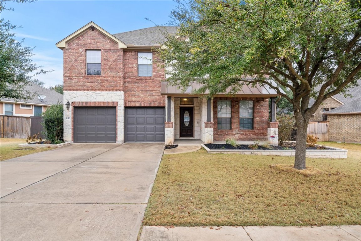 1813 Tall Chief Leander, TX 78641 - Photo 2 of 26 Traditional home featuring concrete driveway, brick siding, an attached garage, and a front yard