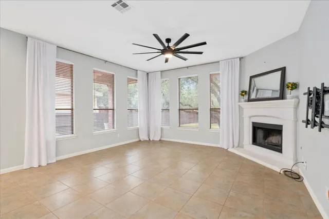 a view of livingroom with fireplace ceiling fan and windows