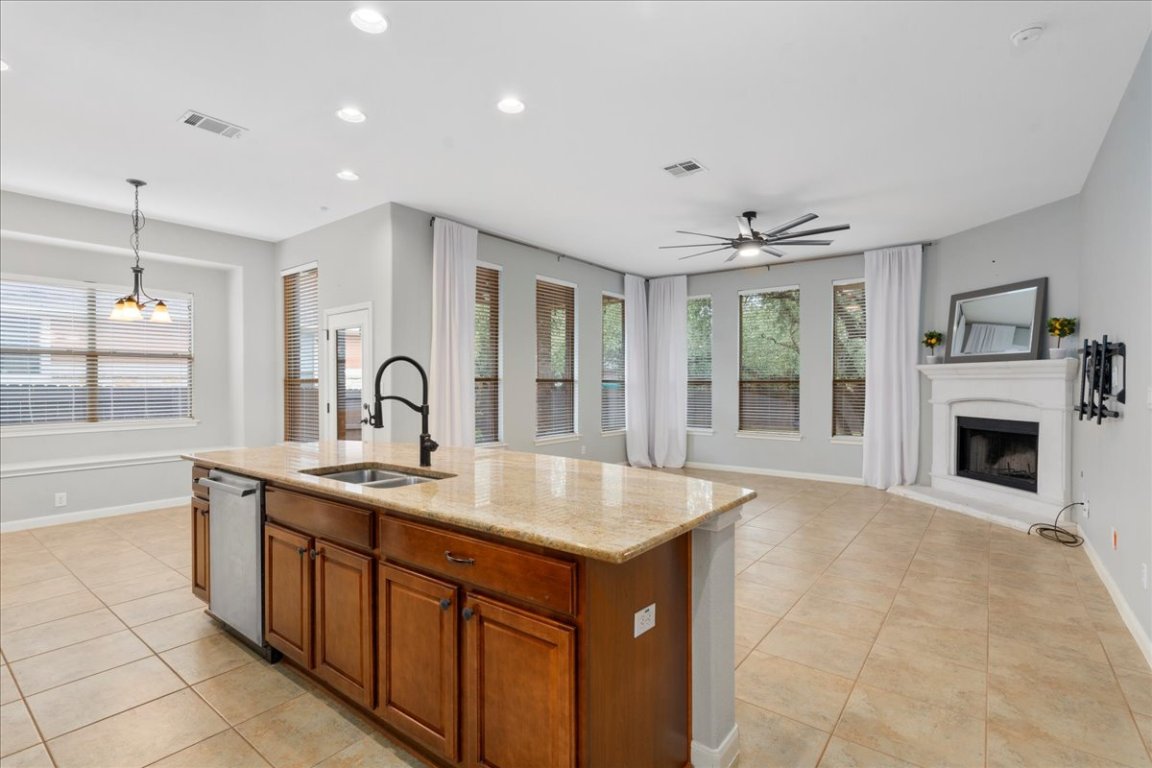 1813 Tall Chief Leander, TX 78641 - Photo 5 of 26 Kitchen featuring visible vents, light tile patterned flooring, a fireplace with raised hearth, a sink, and dishwasher