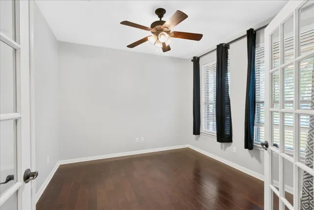 an empty room with windows and ceiling fan