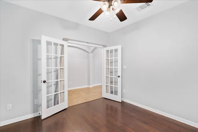 an empty room with wooden floor closet and windows