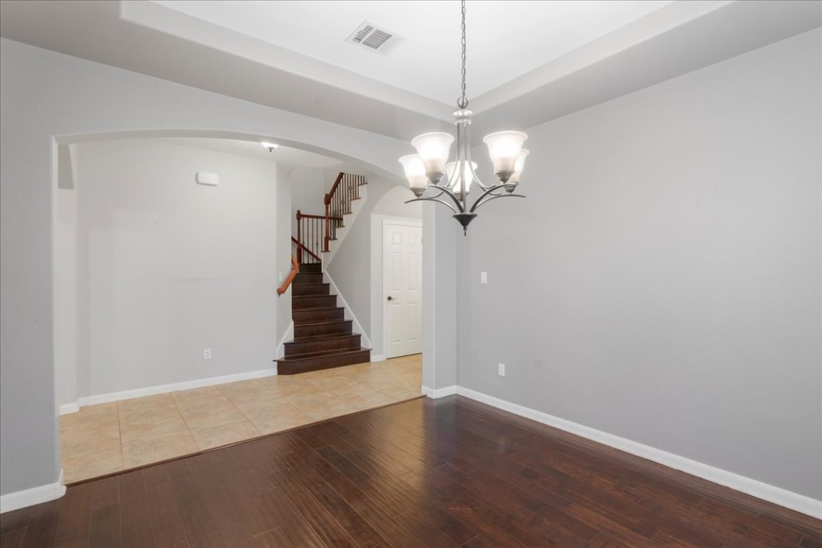 1813 Tall Chief Leander, TX 78641 - Photo 10 of 26 Unfurnished room featuring visible vents, arched walkways, stairway, a chandelier, and hardwood / wood-style floors