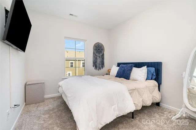 a bedroom with a bed a flat screen tv and windows