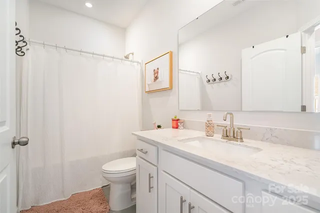 a bathroom with a granite countertop sink mirror vanity and toilet