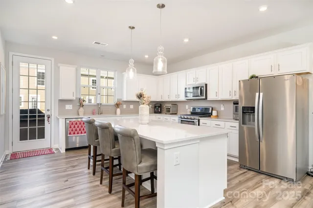 a kitchen with stainless steel appliances a refrigerator a stove a sink dishwasher and white countertops with wooden floor