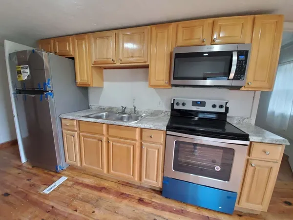 a view of kitchen with stainless steel appliances wooden floor and chair