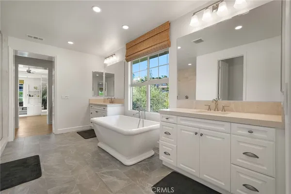 a bathroom with a bathtub a sink a window and mirror