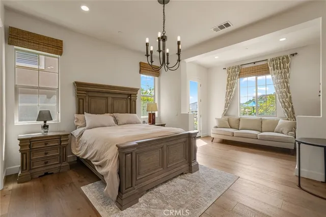 a bedroom with a large bed a chandelier and windows