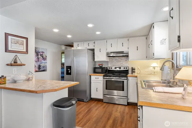 a kitchen with kitchen island granite countertop a sink cabinets and stainless steel appliances