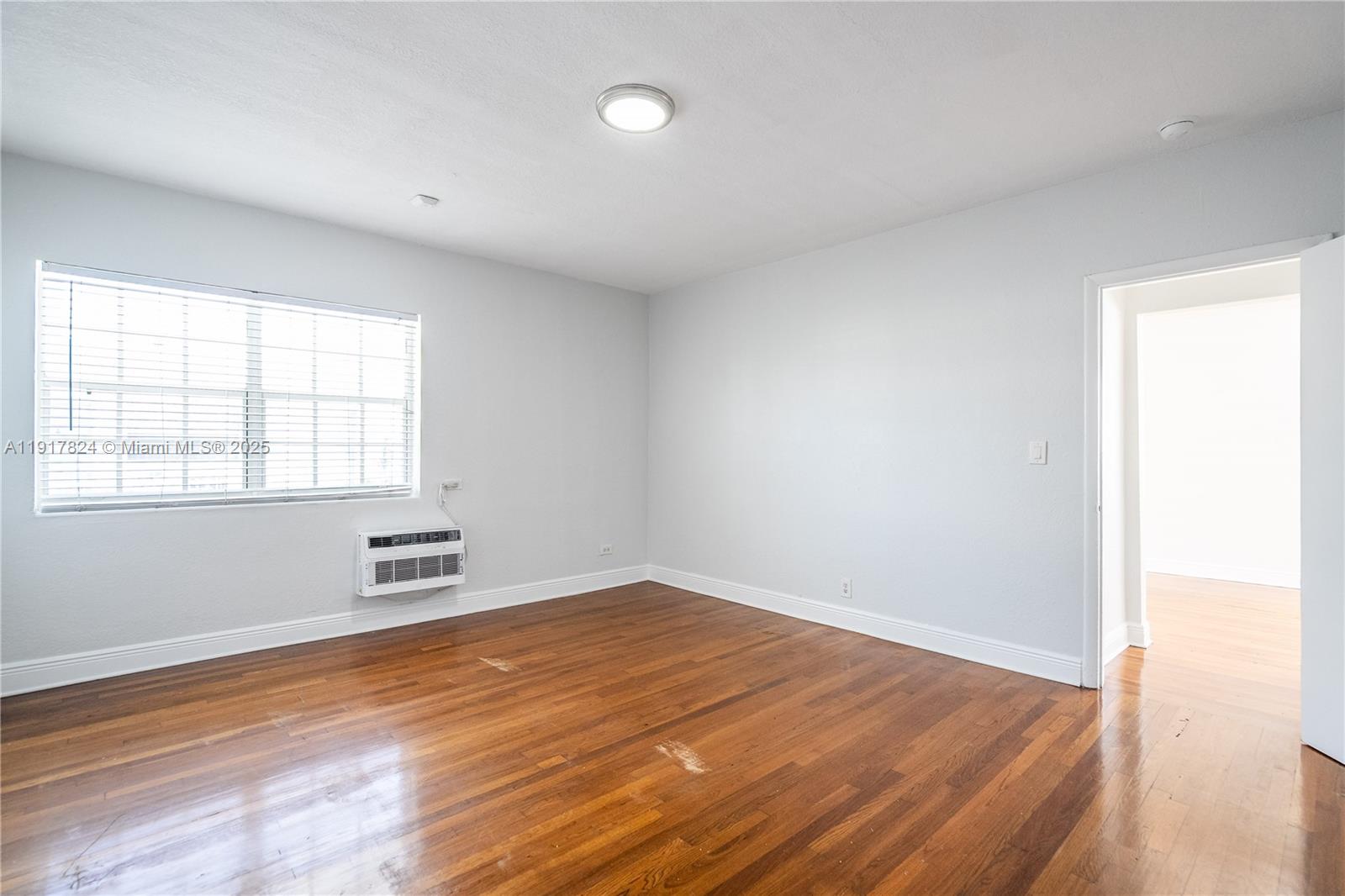 330 84th Street, Unit 12 Miami Beach, FL 33141 - Photo 12 of 20 an empty room with wooden floor and windows