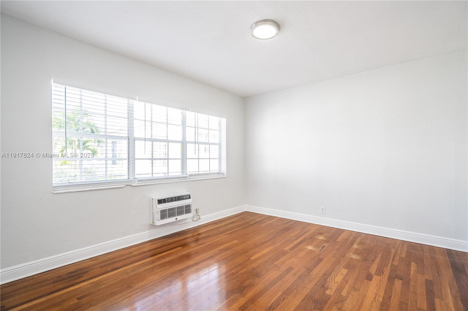 330 84th Street, Unit 12 Miami Beach, FL 33141 - Photo 14 of 20 an empty room with wooden floor and windows