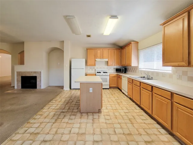 a large kitchen with stainless steel appliances granite countertop a stove a sink dishwasher a microwave oven and a refrigerator with wooden cabinets