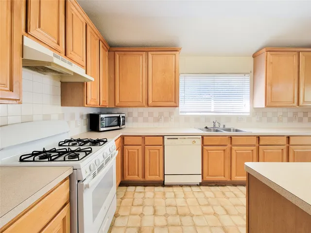 a kitchen with stainless steel appliances granite countertop a stove a sink and a microwave