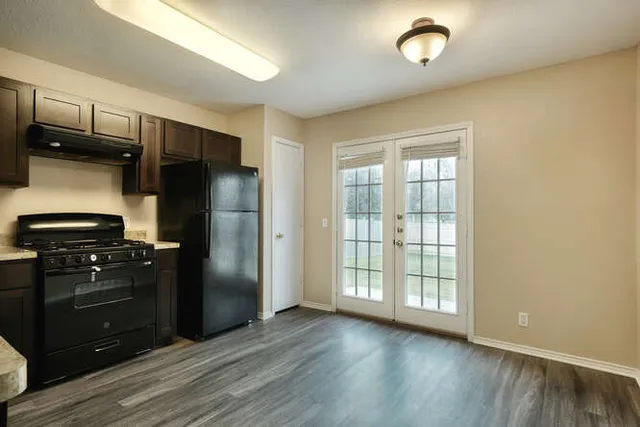 a kitchen with granite countertop a refrigerator and a stove top oven