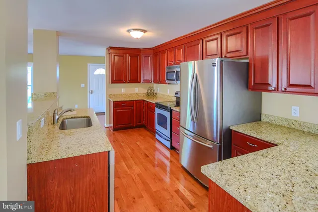 a kitchen with stainless steel appliances granite countertop a refrigerator a sink dishwasher stove and oven