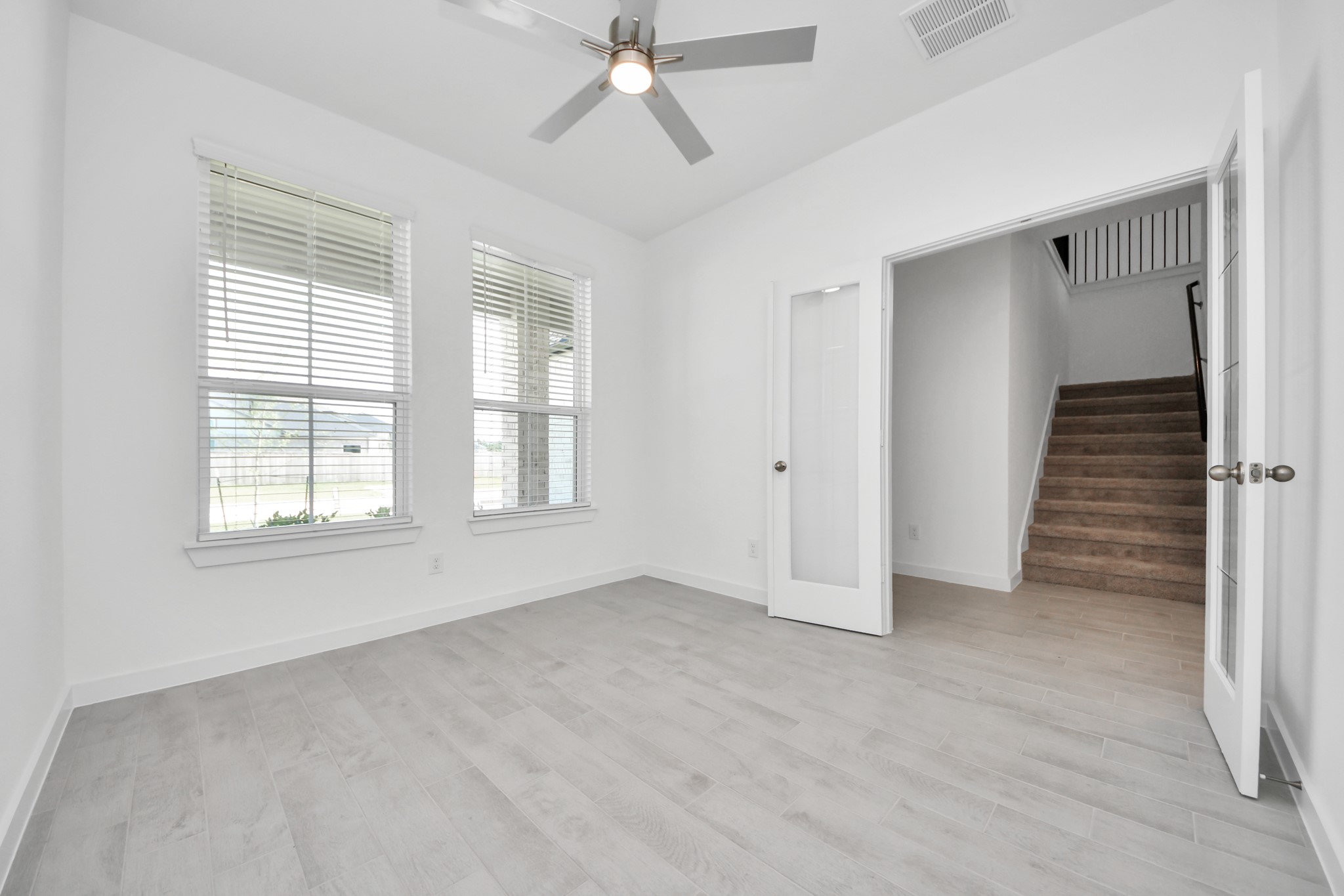 2926 Bury Park Dr Spring Spring, TX 77373 - Photo 7 of 40 Experience the perfect blend of sophistication and warmth in this home office, boasting elegant wood-look tile flooring and flooded with natural light from expansive windows and French doors.