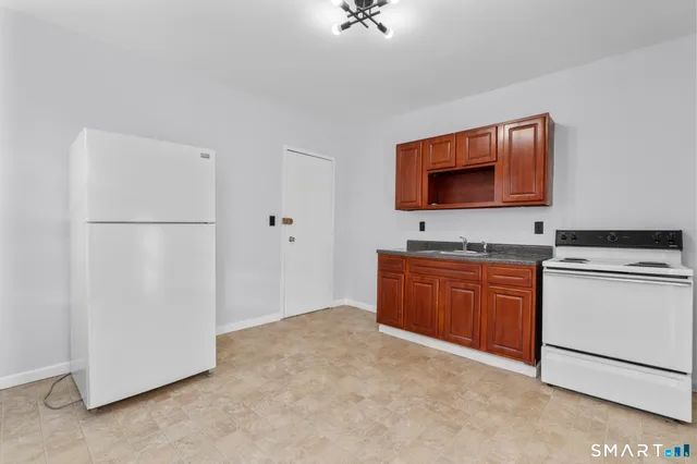 a kitchen with granite countertop a refrigerator and a stove top oven